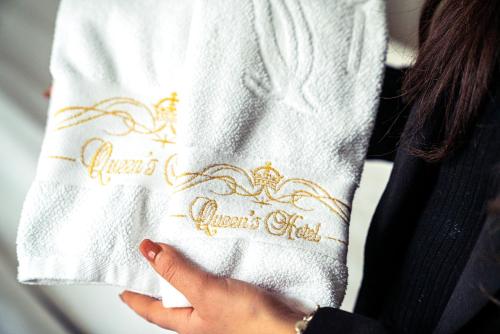 a woman holding a white napkin with a crown design on it at Queen's Hotel by First Hotels in Stockholm