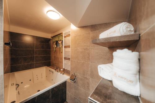 a bathroom with a tub and a sink and towels at Becirk in Štramberk