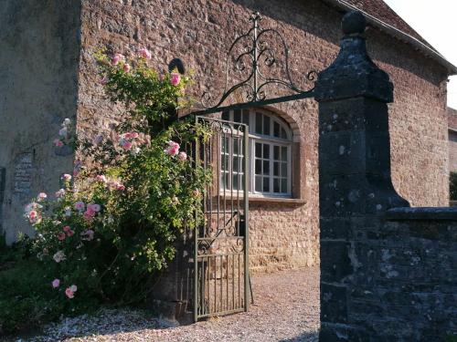 a gate to a brick building with a flowering bush at au château in Miserey-Salines