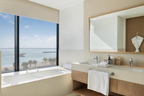 ein Bad mit einer Badewanne und einem großen Fenster in der Unterkunft Vida Beach Resort Marassi Al Bahrain in Manama
