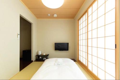 a bedroom with a large bed and a tv at Karasuma Rokujo Hotel / Vacation STAY 3038 in Kyoto