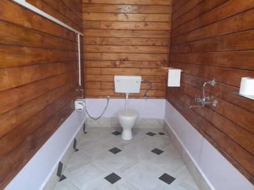 a bathroom with wooden walls and a toilet and a tub at Aquila Boutique Resort Agonda in Canacona