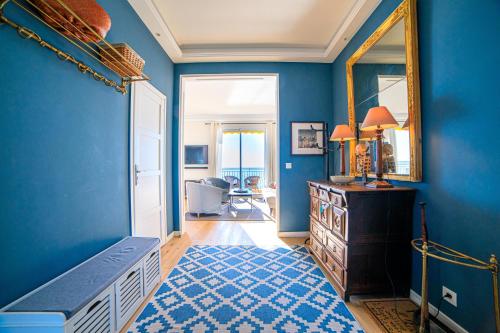 Cette chambre est dotée d'un mur bleu avec un miroir et une commode. dans l'établissement Magnifique Appartement Sur La Plage Près Du Centre - Palais De La Plage, à Cannes