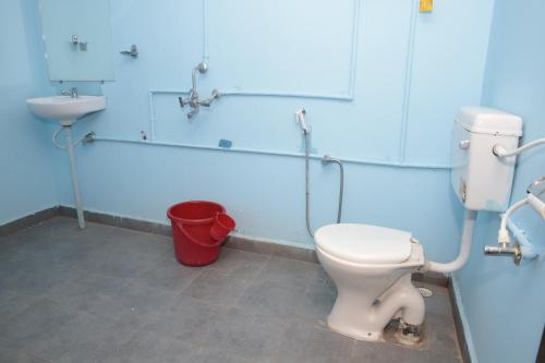 a bathroom with a toilet and a sink and a bucket at ORANGE SKY INN HOLIDAY HOME in Canacona