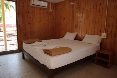 a bedroom with a bed with white sheets and wooden walls at ORANGE SKY INN HOLIDAY HOME in Canacona