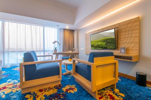 a hotel room with two chairs and a television at Hotel Metland Smara Kertajati in Majalengka