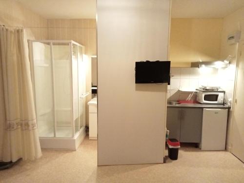a small kitchen with a refrigerator and a microwave at Hôtel Restaurant de la Gare (Studios Du Breuil) in La Roche-Posay