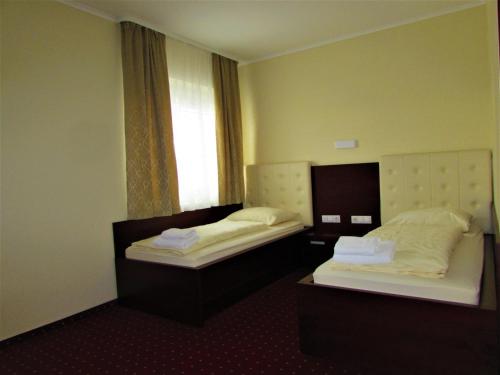 2 Betten in einem Hotelzimmer mit Fenster in der Unterkunft Gostišče Zvezda Ljutomer in Ljutomer