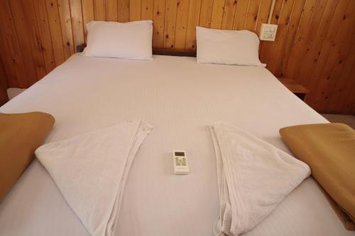 a large white bed with two pillows and a remote control at ORANGE SKY INN HOLIDAY HOME in Canacona
