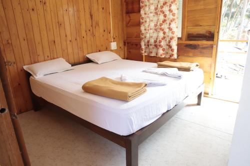 a bed with white sheets and towels on it at ORANGE SKY INN HOLIDAY HOME in Canacona