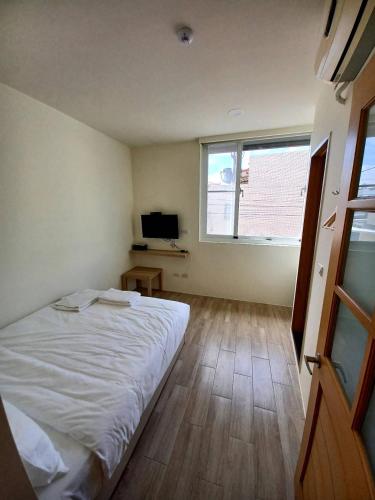 a bedroom with a white bed and a television at Kenting Ocean World Diving II in Hengchun