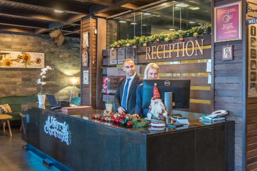 a man and woman standing at a reception desk at St George Ski & Holiday - Half Board & All Inclusive in Bansko