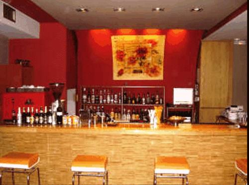 un bar dans un restaurant avec des murs et des chaises rouges dans l'établissement Aegli Hotel, à Grevená