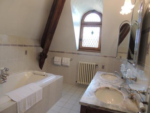 baño con 2 lavabos, bañera y ventana en Domaine de La Vitrolle, en Limeuil