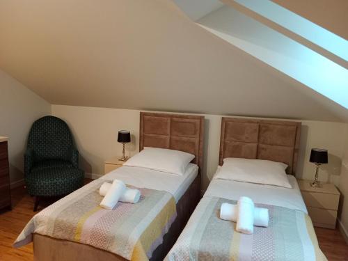 two twin beds in a room with a chair at Apartamenty Radom Klwatecka 20 in Radom