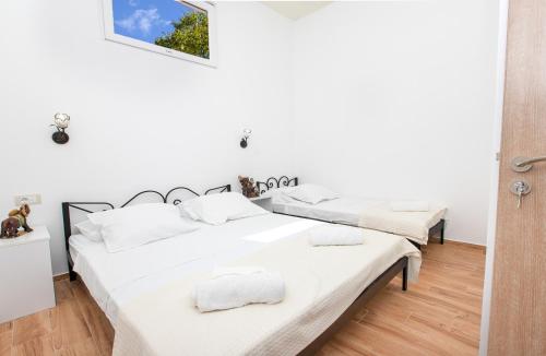 2 łóżka w pokoju z białymi ścianami i drewnianą podłogą w obiekcie Apartments Golden View w Kotorze