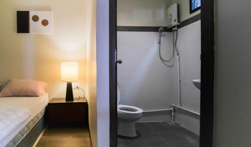 a bathroom with a shower and a toilet and a bed at BOHO Hostel in Ko Lanta