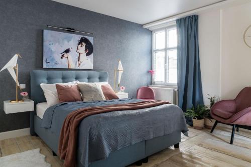 1 dormitorio con 1 cama azul y 1 silla rosa en Sanhaus Apartments - Apartamenty Toledo - 3 minuty od plaży, en Sopot
