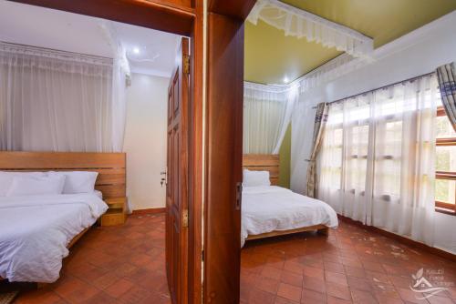 a bedroom with two beds and a window at Kisubi Forest Cottages in Entebbe