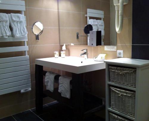 La salle de bains est pourvue d'un lavabo, d'un miroir et de serviettes. dans l'établissement Hotel Le Bussy, à Montsoreau