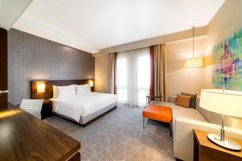 a hotel room with a bed and a couch at Hyatt Place Dubai Wasl District Residences in Dubai