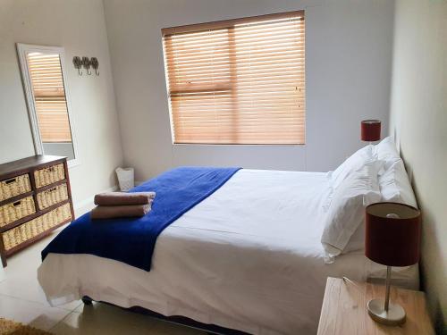 a bedroom with a large white bed and two windows at Acacia Four Seven Self-Catering in Swakopmund