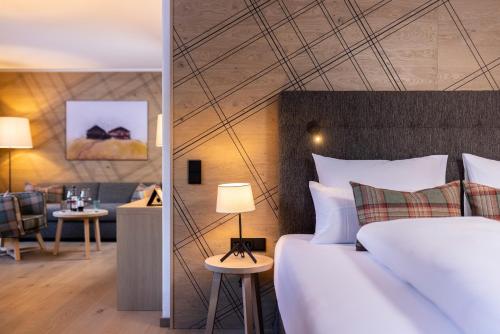 a bedroom with a bed and a living room at Defereggental Hotel & Resort in Sankt Veit in Defereggen