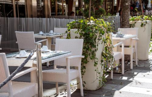 a row of tables and chairs with plants on them at Bellini Relais in Lignano Sabbiadoro