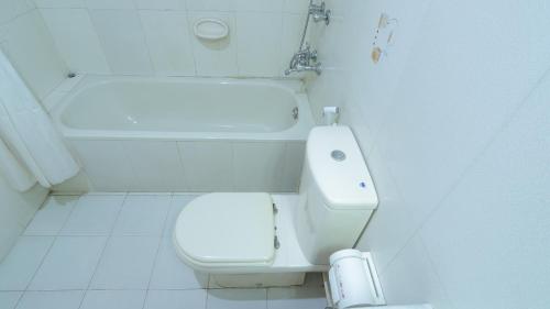 a white bathroom with a toilet and a bath tub at Hotel Metro International in Sylhet