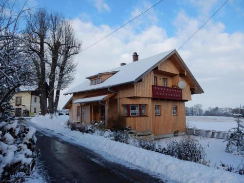 a wooden house with snow on the side of a road at Ferienhaus Wankner in Tittmoning