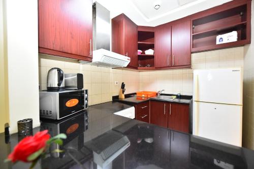a kitchen with wooden cabinets and a white refrigerator at Luxury Escapes - Budget-Friendly Studio Near Metro - MED67 DG in Dubai