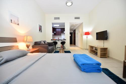 a bedroom with a large bed and a living room at Budget-Friendly Studio Near Metro - Spacious & Calm - VRN in Dubai