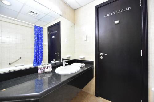 a black bathroom with a sink and a black door at Luxury Escapes - Budget-Friendly Studio Near Metro - MED67 DG in Dubai