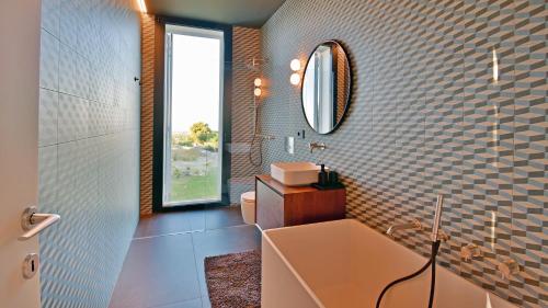 een badkamer met een bad, een wastafel en een spiegel bij VILLA SPECCHIO DI MARE 8, Emma Villas in Polignano a Mare