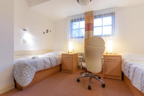 a room with two beds and a chair in it at Penzion Sykovec in Tři Studně