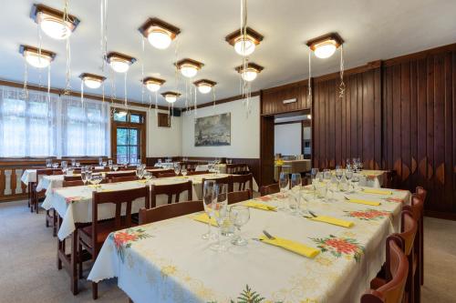 a dining room with tables and chairs and lights at Penzion Sykovec in Tři Studně