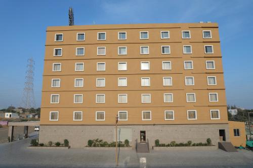 a large brown building with a lot of windows at OAKTREE HOTEL in Morbi