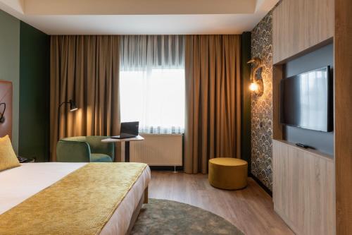 a hotel room with a bed and a television at Shanghai Hotel Holland in Delft