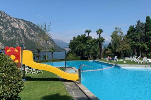 a large swimming pool with a slide in the grass at Luganersee, Pool, Strand, Parkplatz, Suite in Bissone