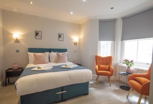 a bedroom with a large bed and two chairs at High Street Kensington by Viridian Apartments in London