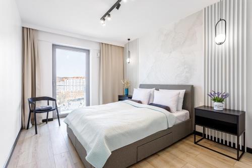 a bedroom with a bed and a chair and a window at Balticus Apartamenty Deluxe Promenada Gwiazd 14 in Międzyzdroje