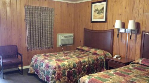 a hotel room with two beds and a chair at Texas Inn Motel in Marshall