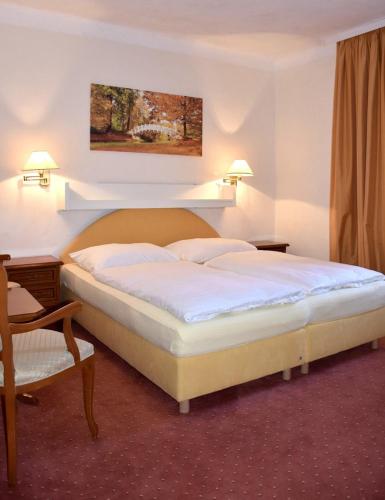 a hotel room with two beds and a chair at Sport Aktiv Pension Spanner - Tauplitz in Bad Mitterndorf