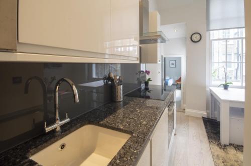 a kitchen with a sink and a counter top at High Street Kensington by Viridian Apartments in London