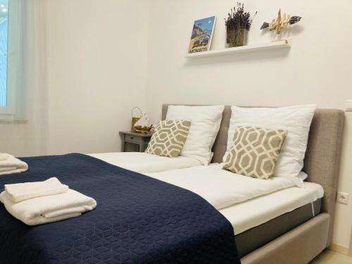 a bed with a blue blanket and pillows on it at ZAWIA APARTMAN in Balatonföldvár