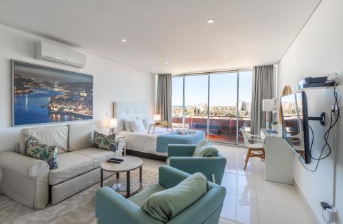 a living room with a bed and a couch and chairs at Estúdios Marina in Vilamoura