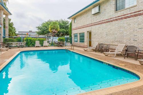 a swimming pool in front of a building with tables and chairs at Days Inn by Wyndham San Antonio Southeast Frost Bank Center in San Antonio