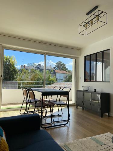 - un salon avec une table, des chaises et une grande fenêtre dans l'établissement Centre-ville au calme grand T2 avec terrasse, à La Rochelle