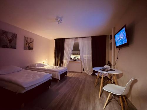 Habitación de hotel con 2 camas, mesa y TV. en 03 Gdynia Centrum - Apartament Mieszkanie dla 2 os en Gdynia