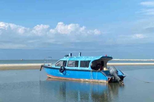 a blue boat is sitting in the water at MELAKA BEACH VILLA ( B TYPE ) in Melaka